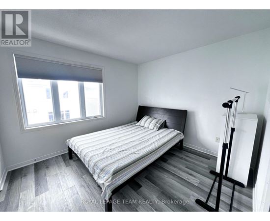 A bedroom with a bed, wooden floors, and a window.