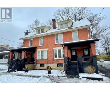 A red brick house with a black front porch and stairs.
