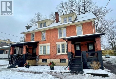A red brick house with a black front porch and stairs.