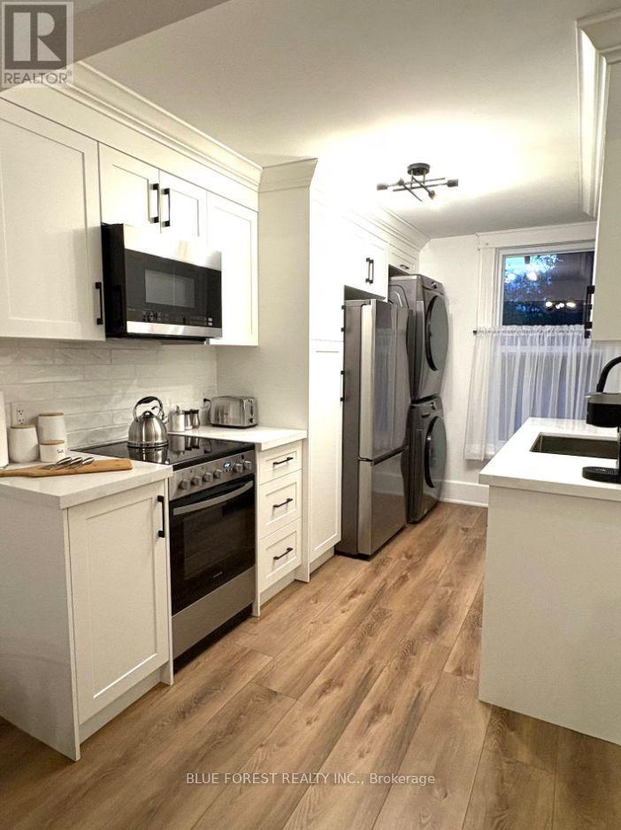 A kitchen with white cabinets and wooden floors.