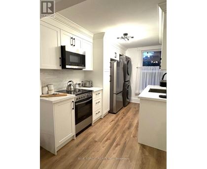 A kitchen with white cabinets and wooden floors.