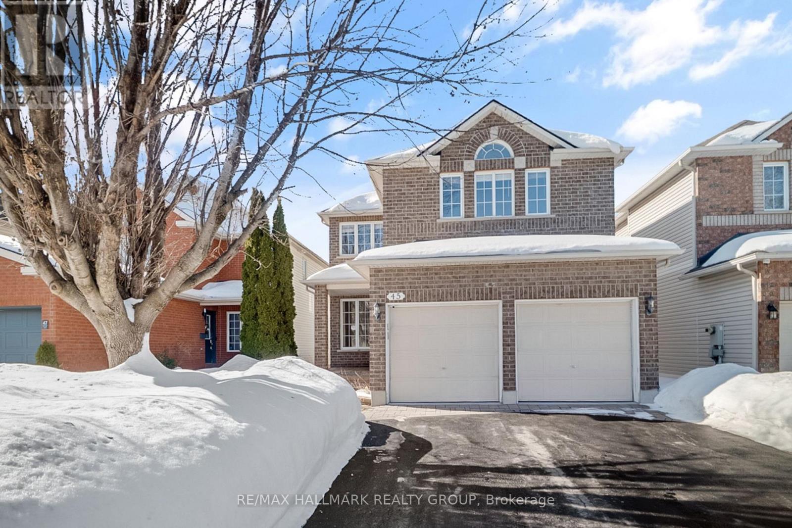A large house with a white garage door is surrounded by snow.