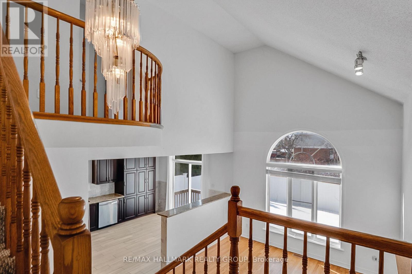 A chandelier hangs over a staircase in a spacious room.