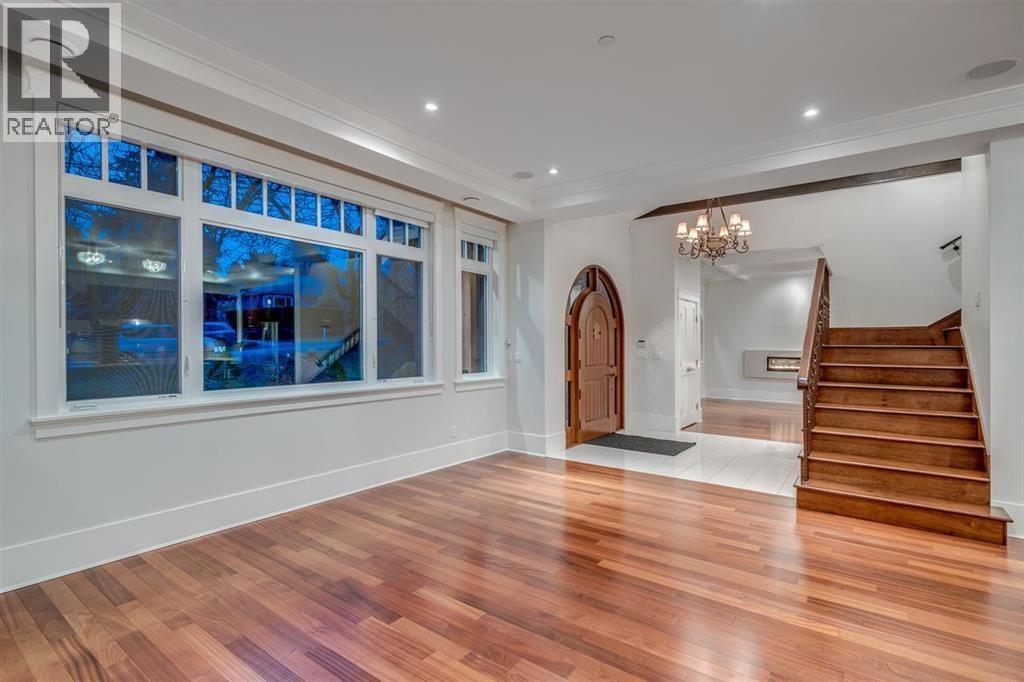 A spacious room with wooden floors and a staircase leading to the upper level.