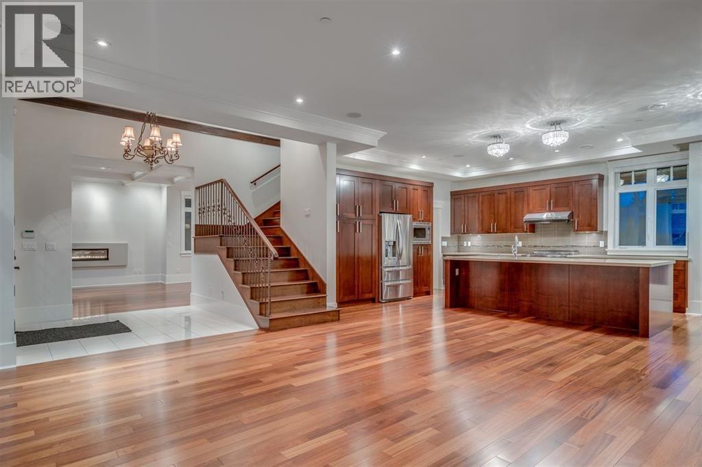 A spacious kitchen with wooden floors and a staircase leading to the upper level.