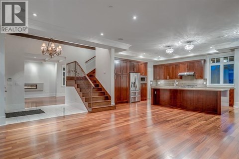 A spacious kitchen with wooden floors and a staircase leading to the upper level.