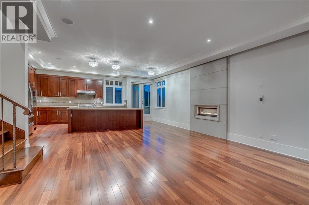 A spacious living room with hardwood floors and a staircase on the left side.