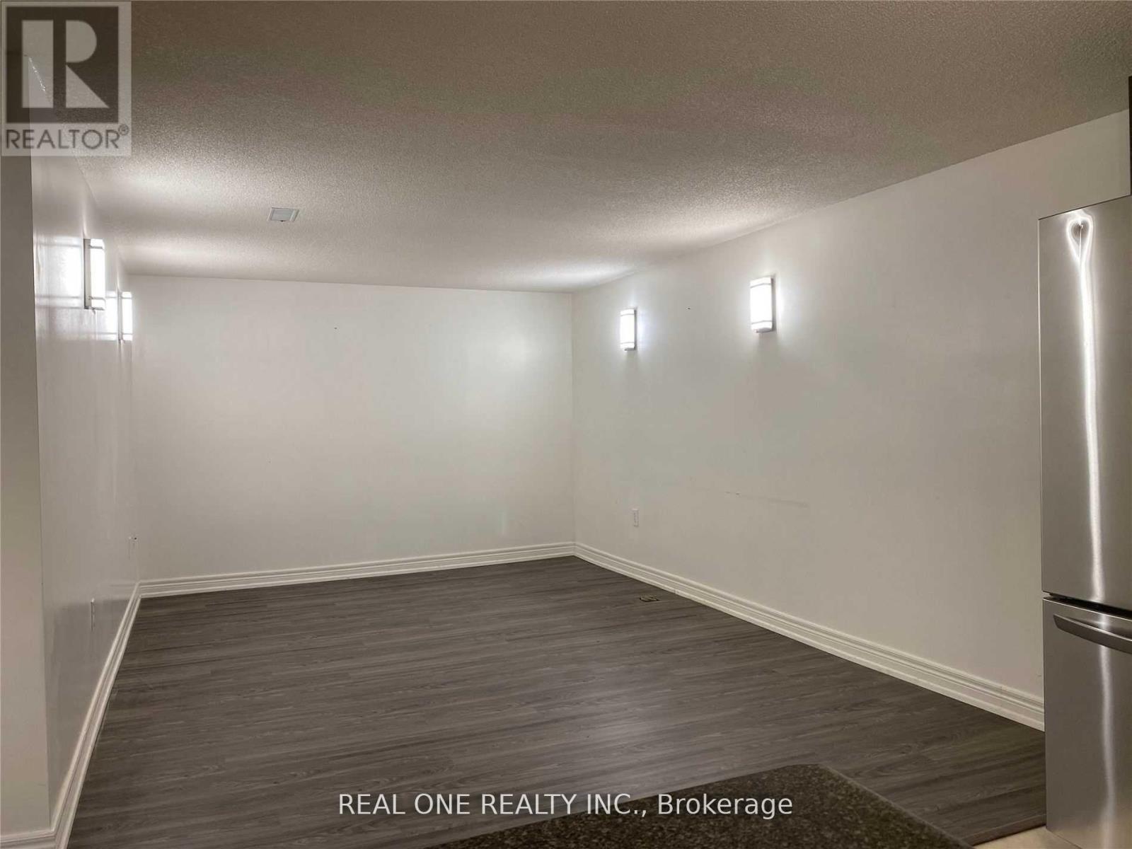 A room with a brokerage sign from REAL ONE REALTY INC.