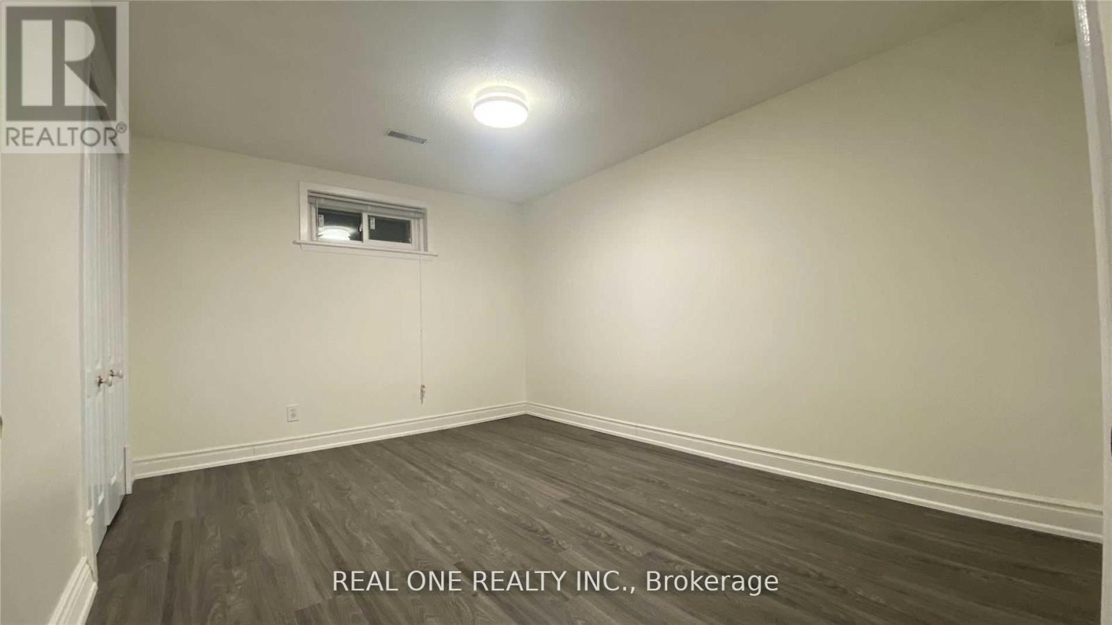 A room with a window and a door, with the text "REAL ONE REALTY INC., Brokerage" on the bottom.