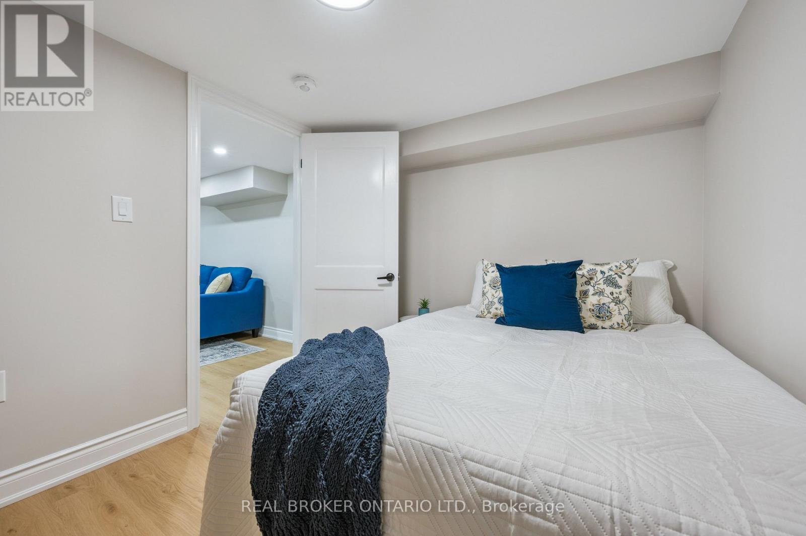 A bedroom with a white bed and a blue chair in the corner.