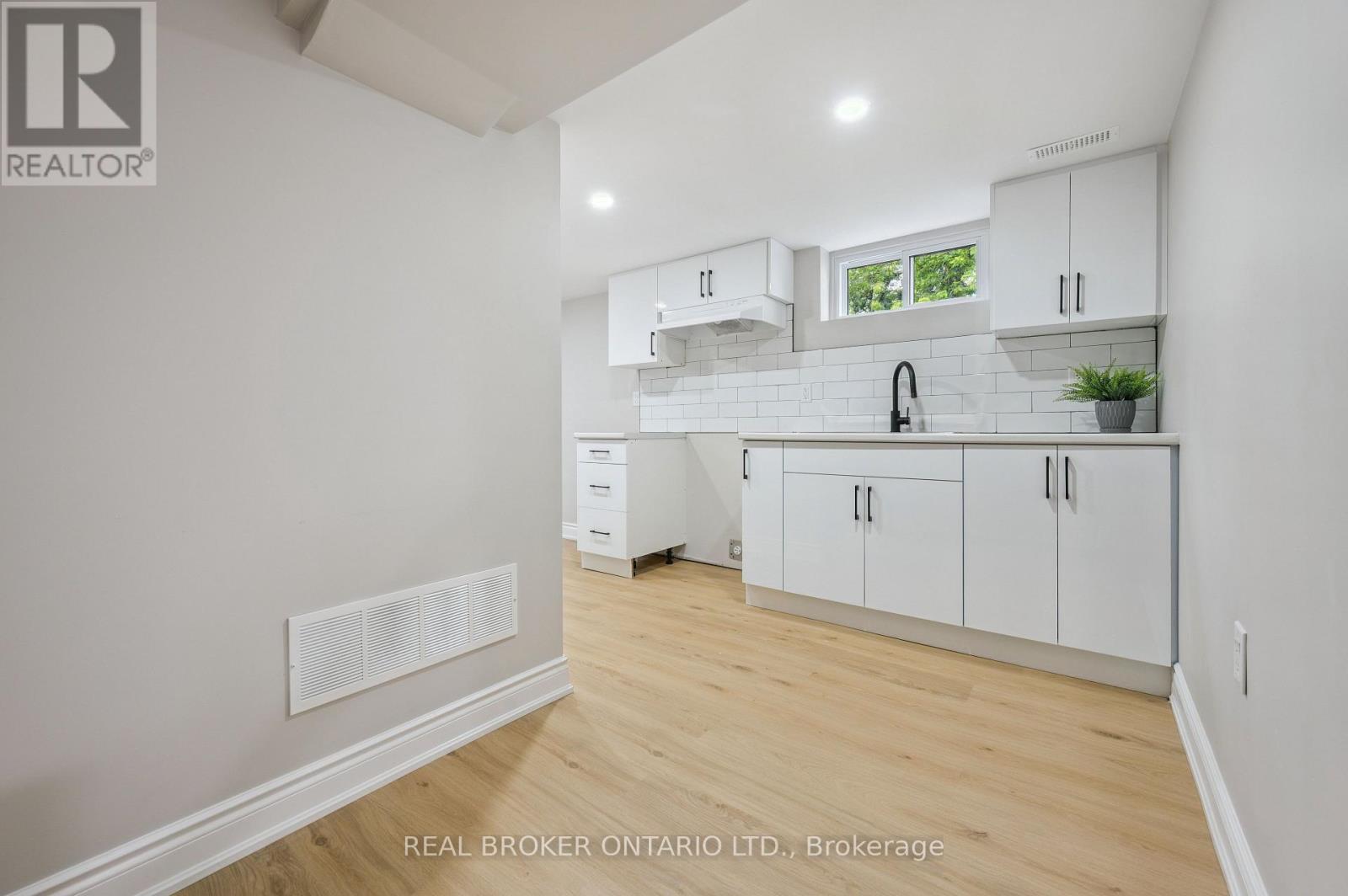 A white kitchen with wooden floors and white cabinets.