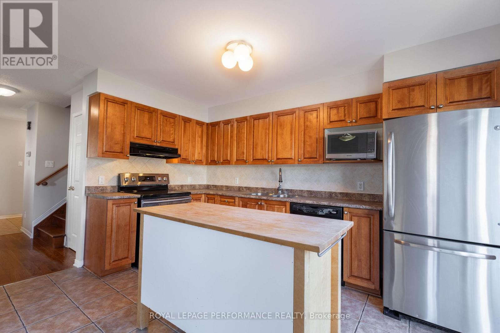 A kitchen with wooden cabinets and a stainless steel refrigerator.