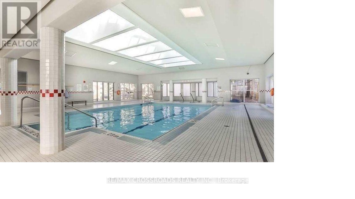 A large indoor swimming pool with a wooden deck and a skylight above.