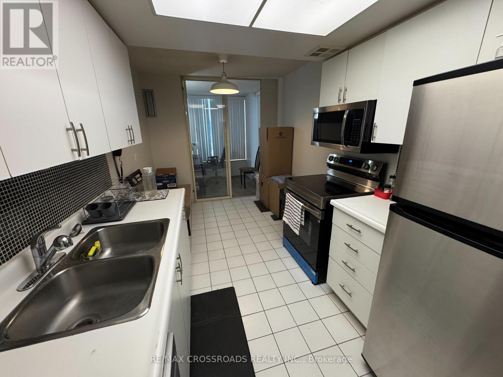 A kitchen with white cabinets and a black fridge.