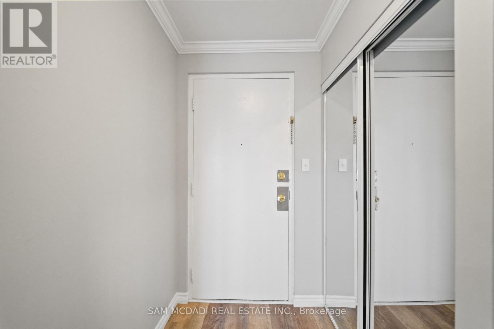 A white door with a gold handle is in a room with white walls.