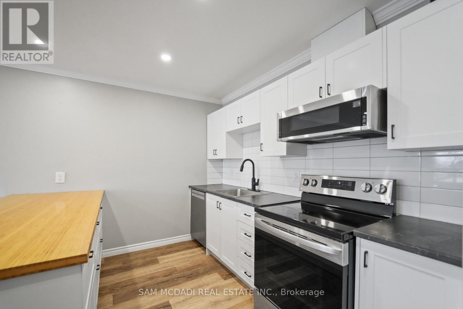 A kitchen with white cabinets and a black stove top oven.