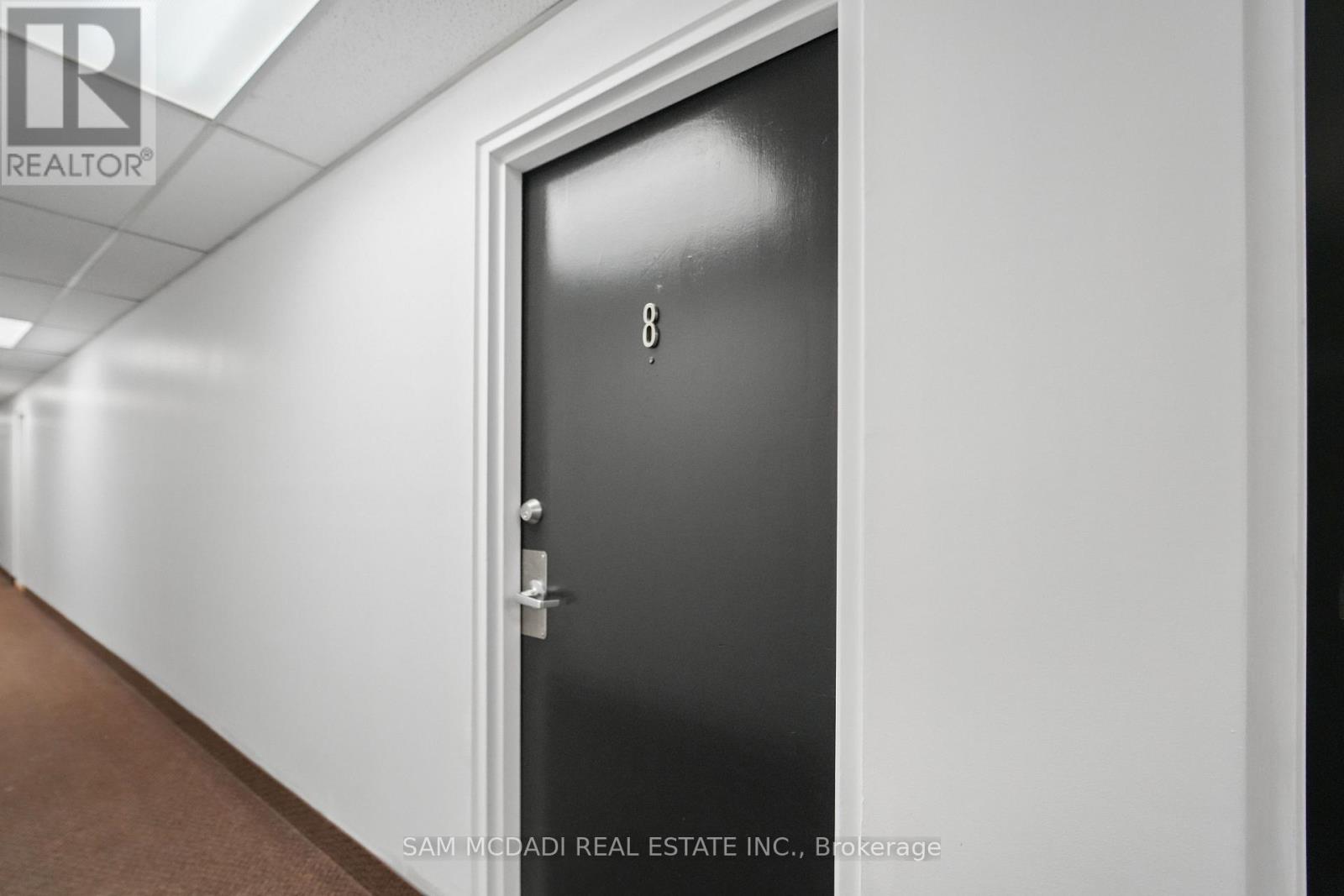 A black door with the number 8 on it in a hallway.