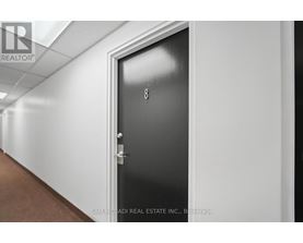 A black door with the number 8 on it in a hallway.