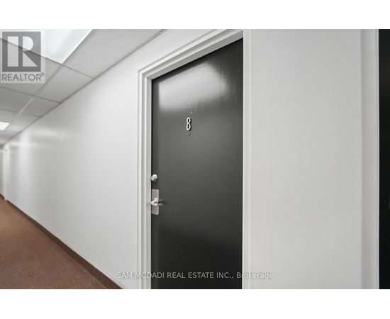A black door with the number 8 on it in a hallway.