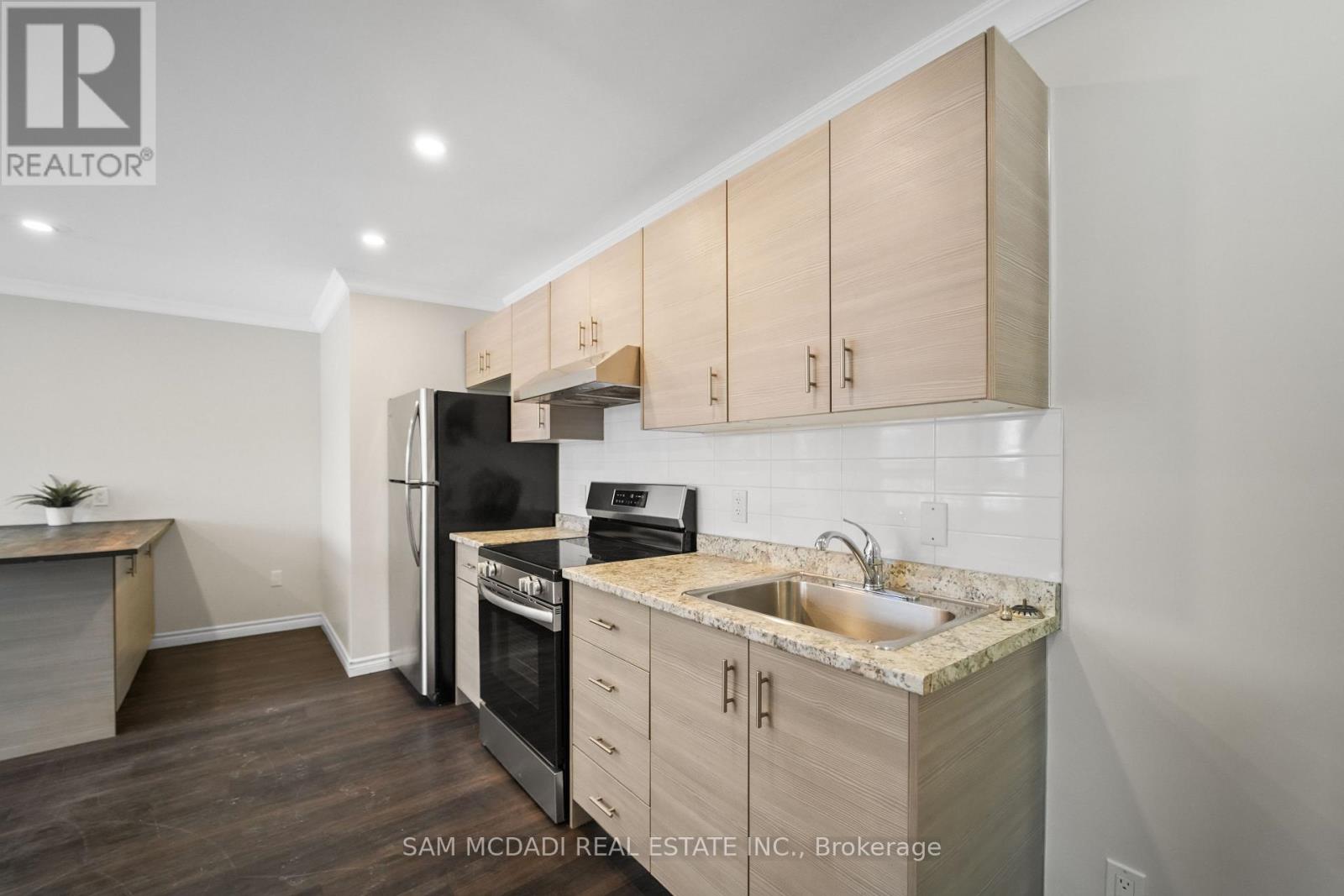 A kitchen with wooden cabinets and a black refrigerator.