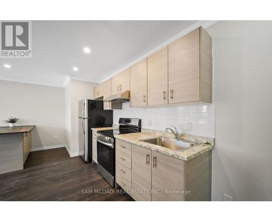 A kitchen with wooden cabinets and a black refrigerator.