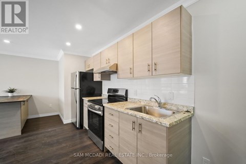 A kitchen with wooden cabinets and a black refrigerator.