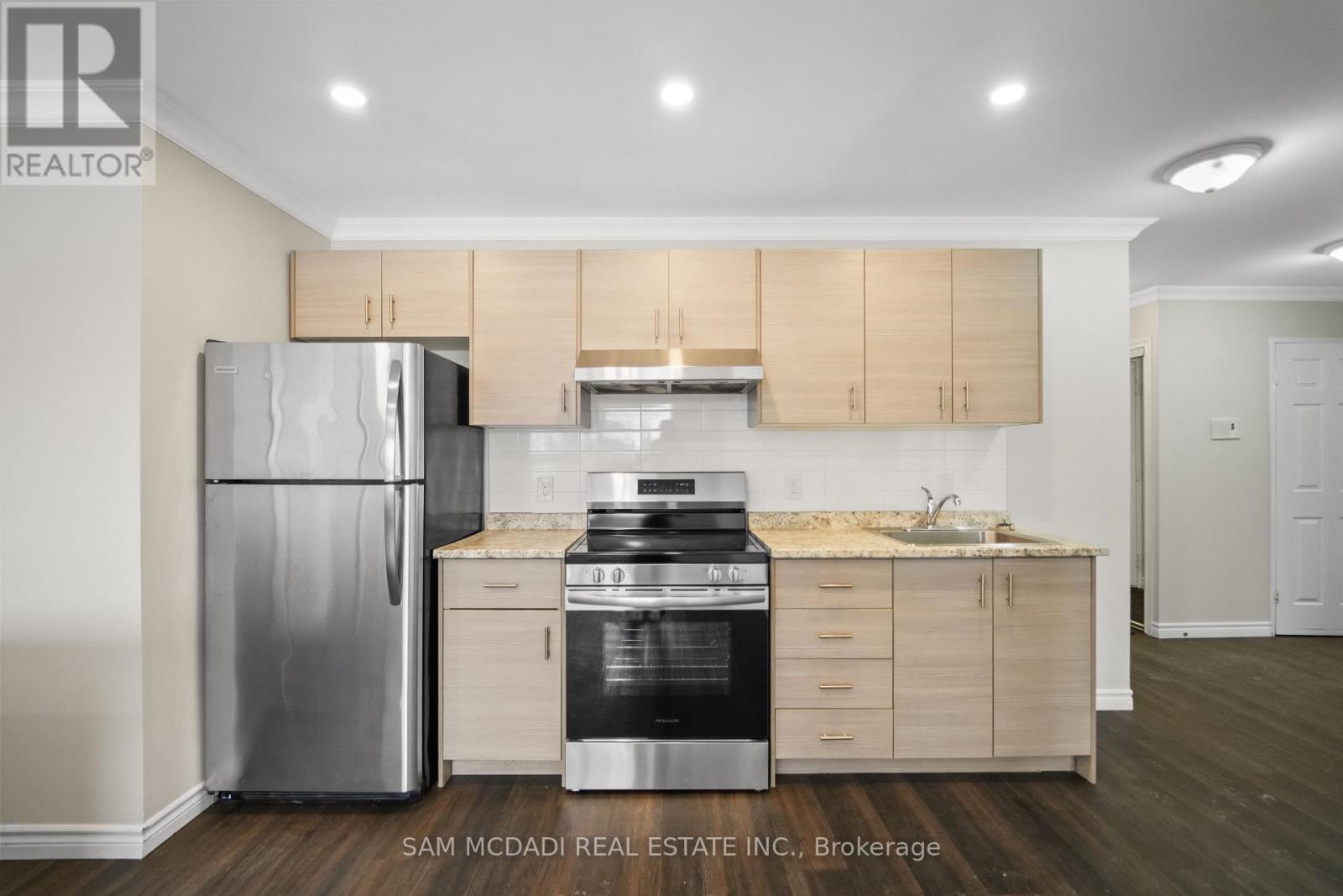 A kitchen with a refrigerator, oven, and cabinets.
