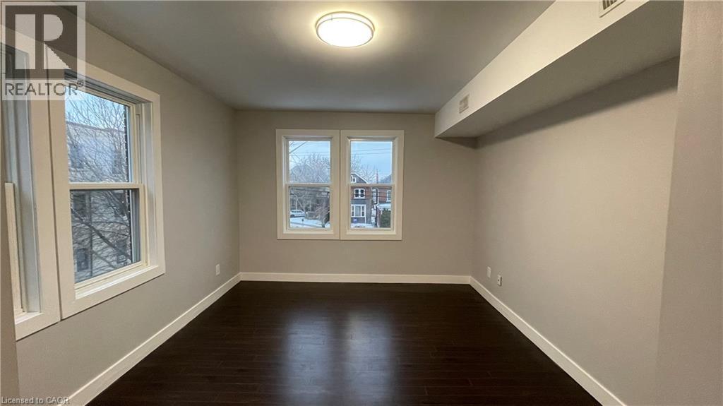 A spacious room with wood flooring and a large window.