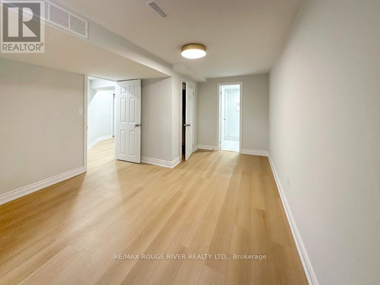 A spacious room with wooden flooring and white walls.