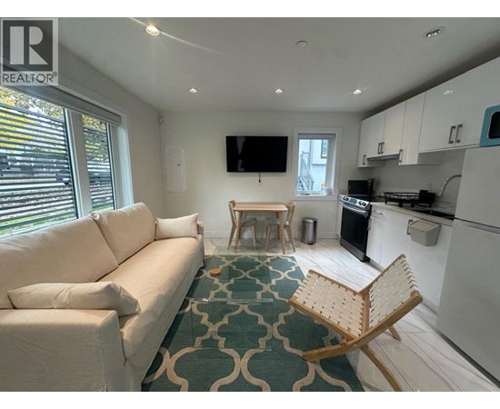 A living room with a white couch and a wooden chair.