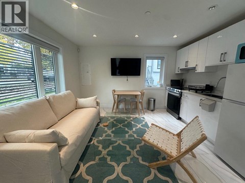 A living room with a white couch and a wooden chair.