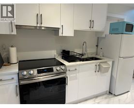 A modern kitchen with white cabinets and a black stove top oven.