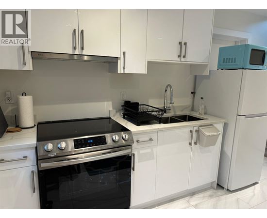 A modern kitchen with white cabinets and a black stove top oven.