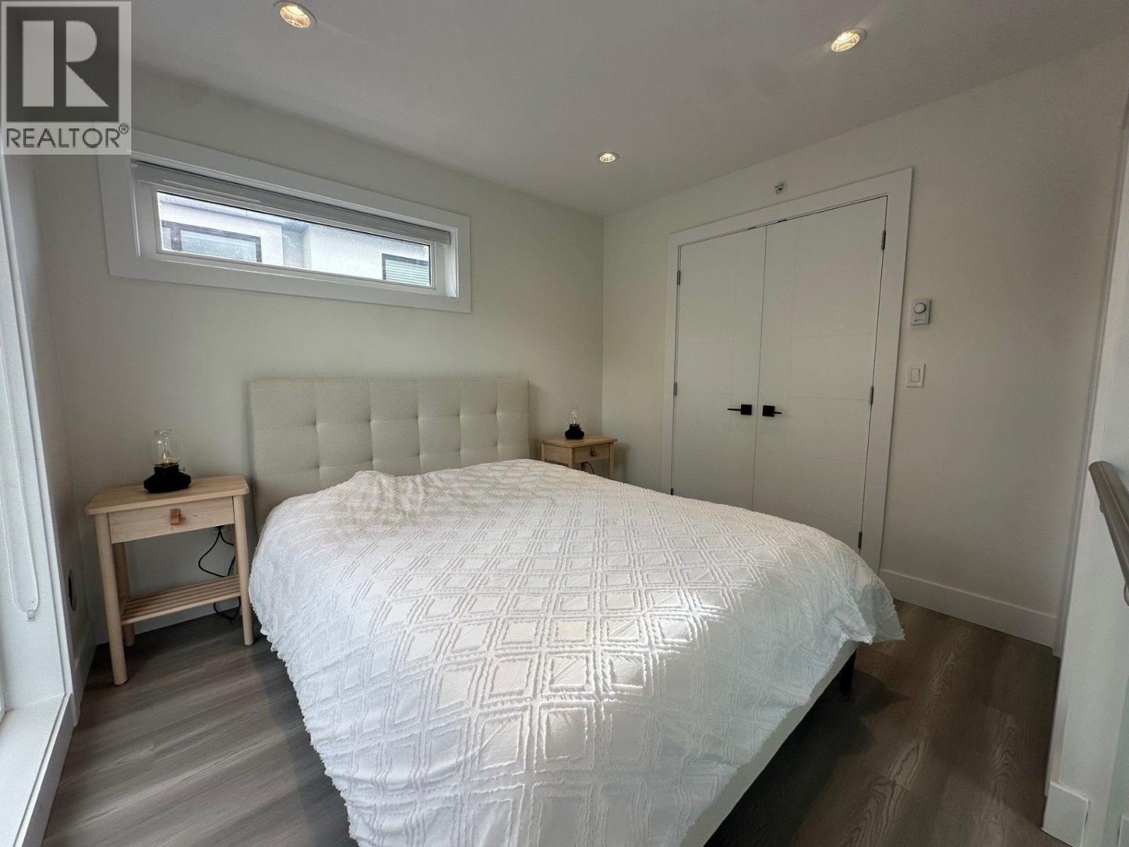 A bedroom with a large bed and a small wooden nightstand.