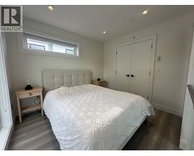 A bedroom with a large bed and a small wooden nightstand.