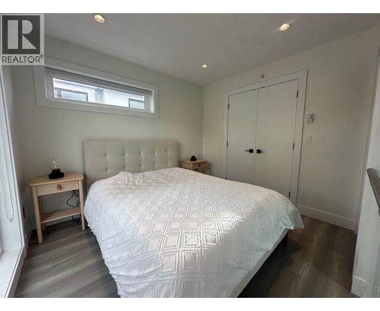 A bedroom with a large bed and a small wooden nightstand.
