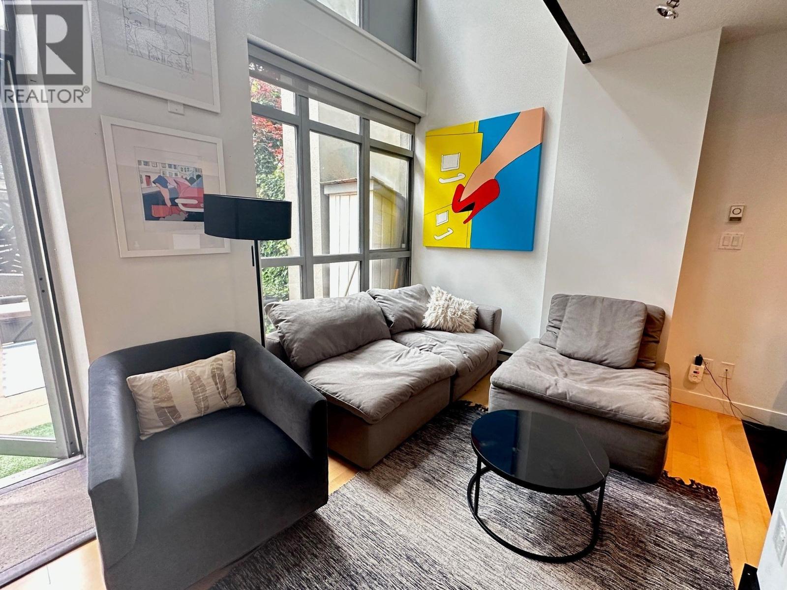 A living room with a grey couch, a black chair and a small table.