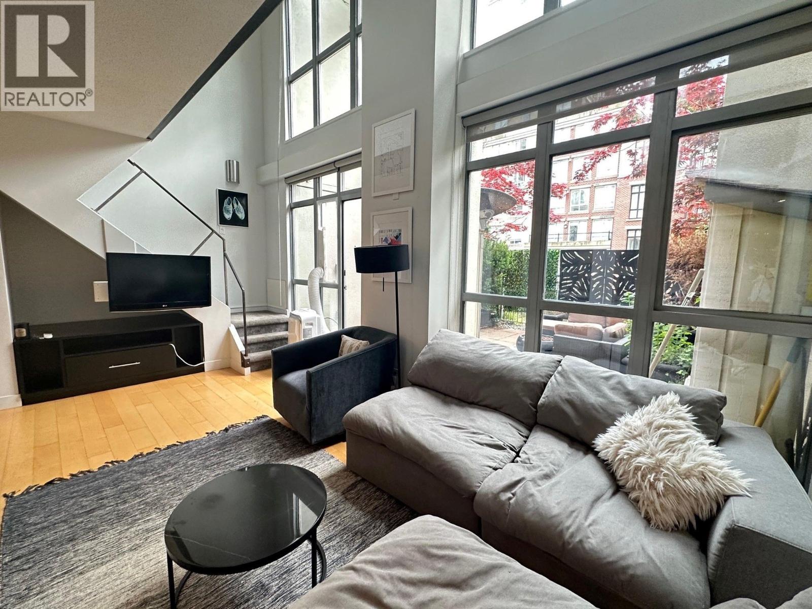 A living room with a grey couch and a black coffee table.