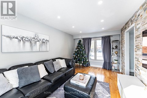 A living room with a black leather couch and a painting on the wall.