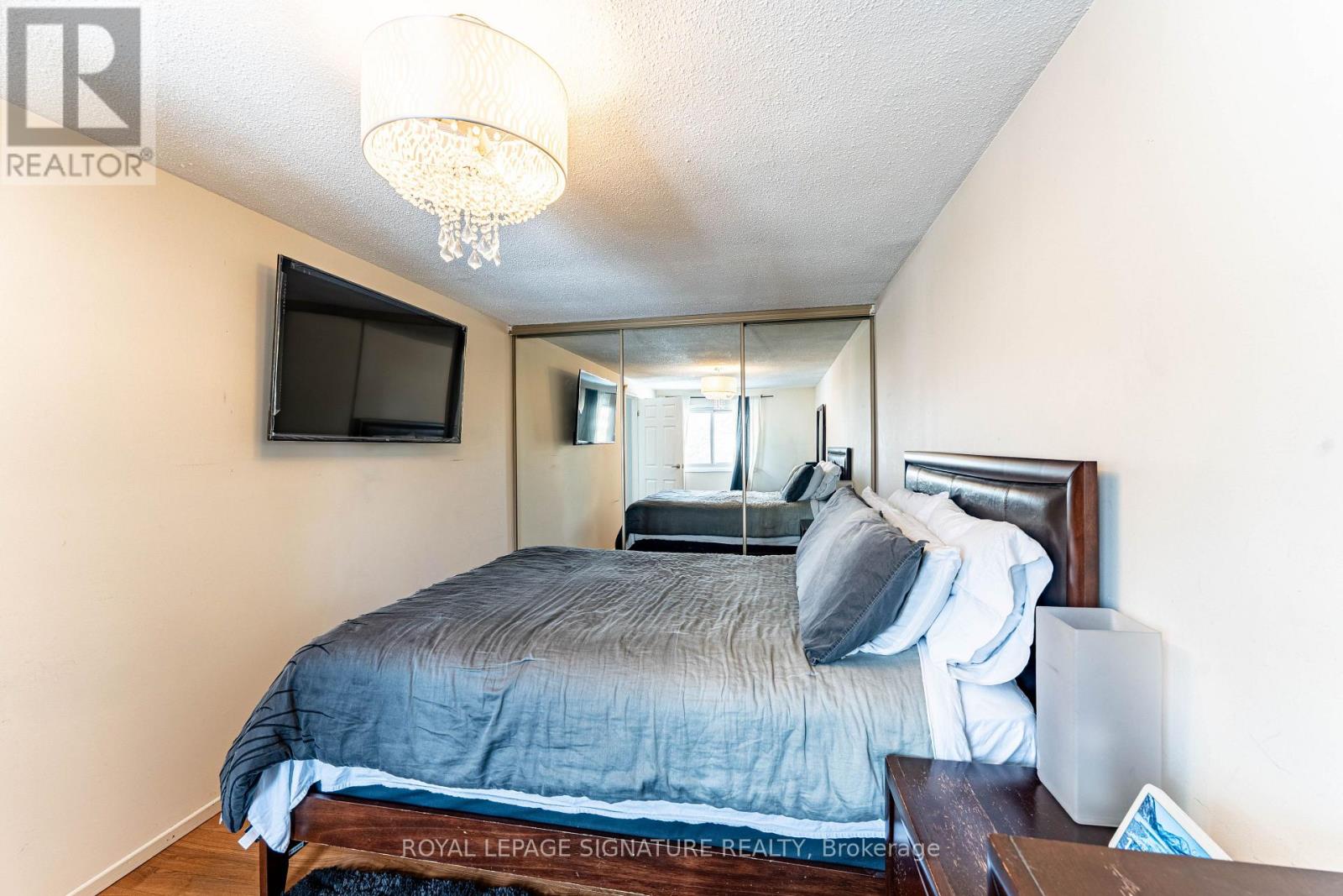 A bedroom with a bed, a television, and a chandelier.