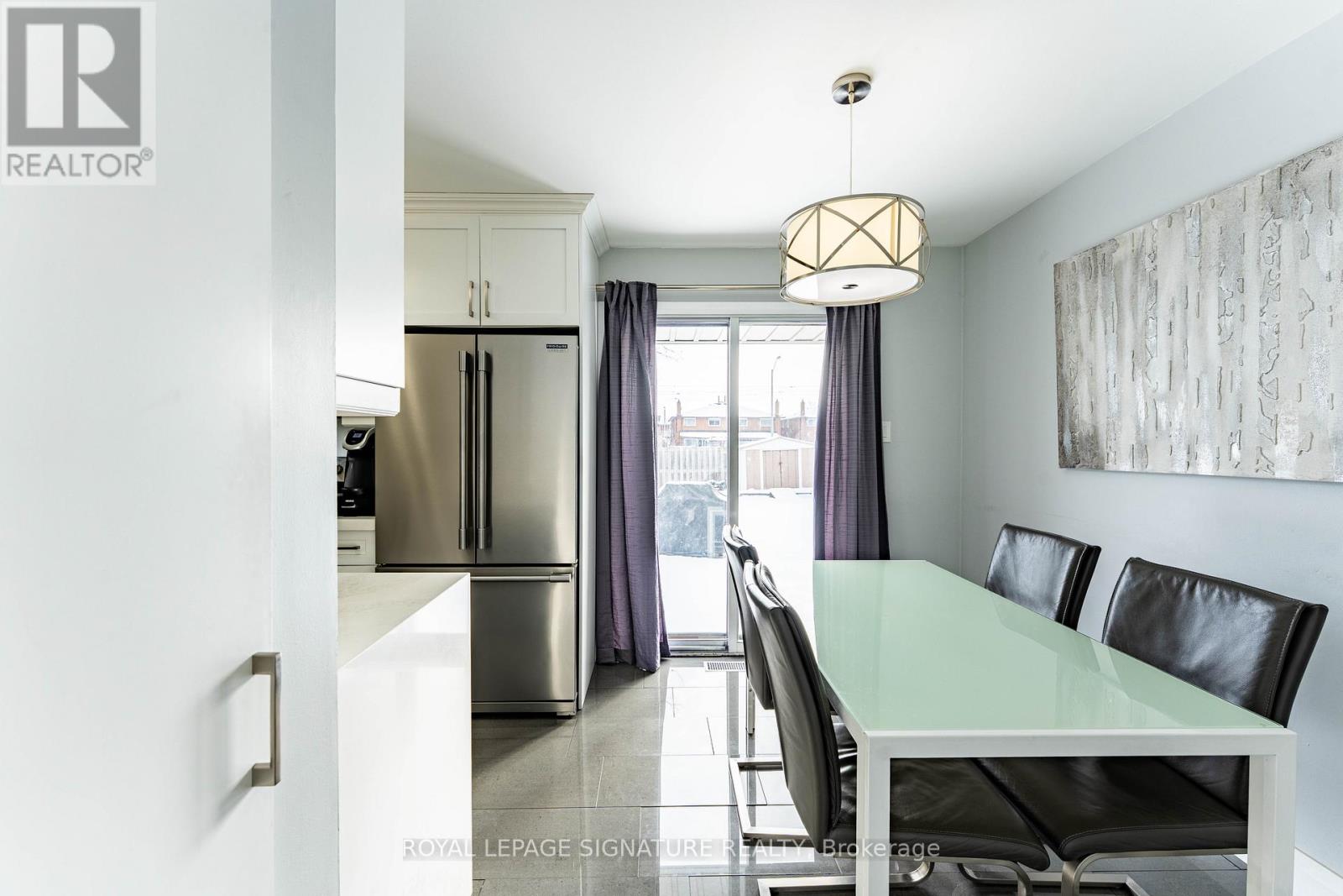 A modern kitchen with a glass table and black chairs.