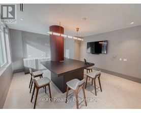 A modern kitchen with a bar stool and a television mounted on the wall.