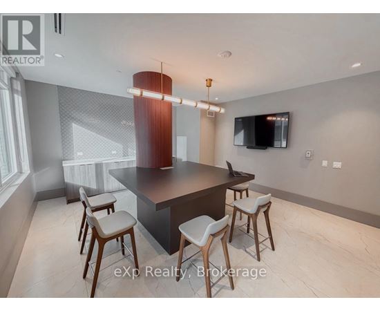 A modern kitchen with a bar stool and a television mounted on the wall.