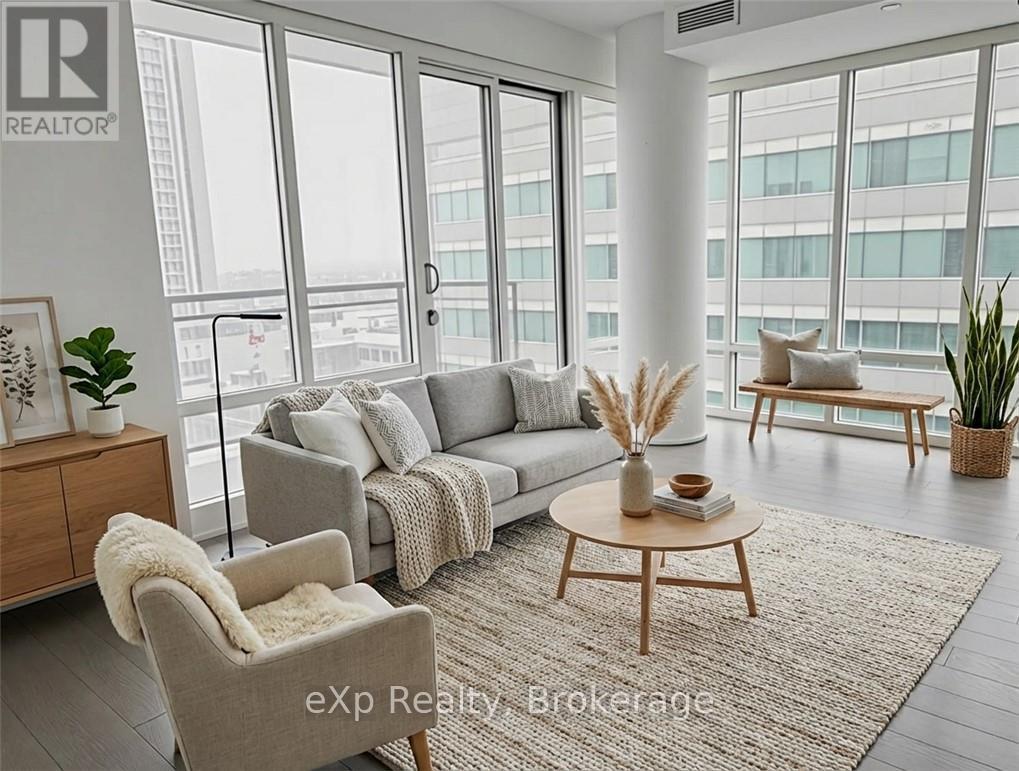 A living room with a grey couch, a wooden coffee table, and a large window with a view of the city.