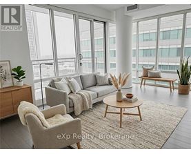 A living room with a grey couch, a wooden coffee table, and a large window with a view of the city.