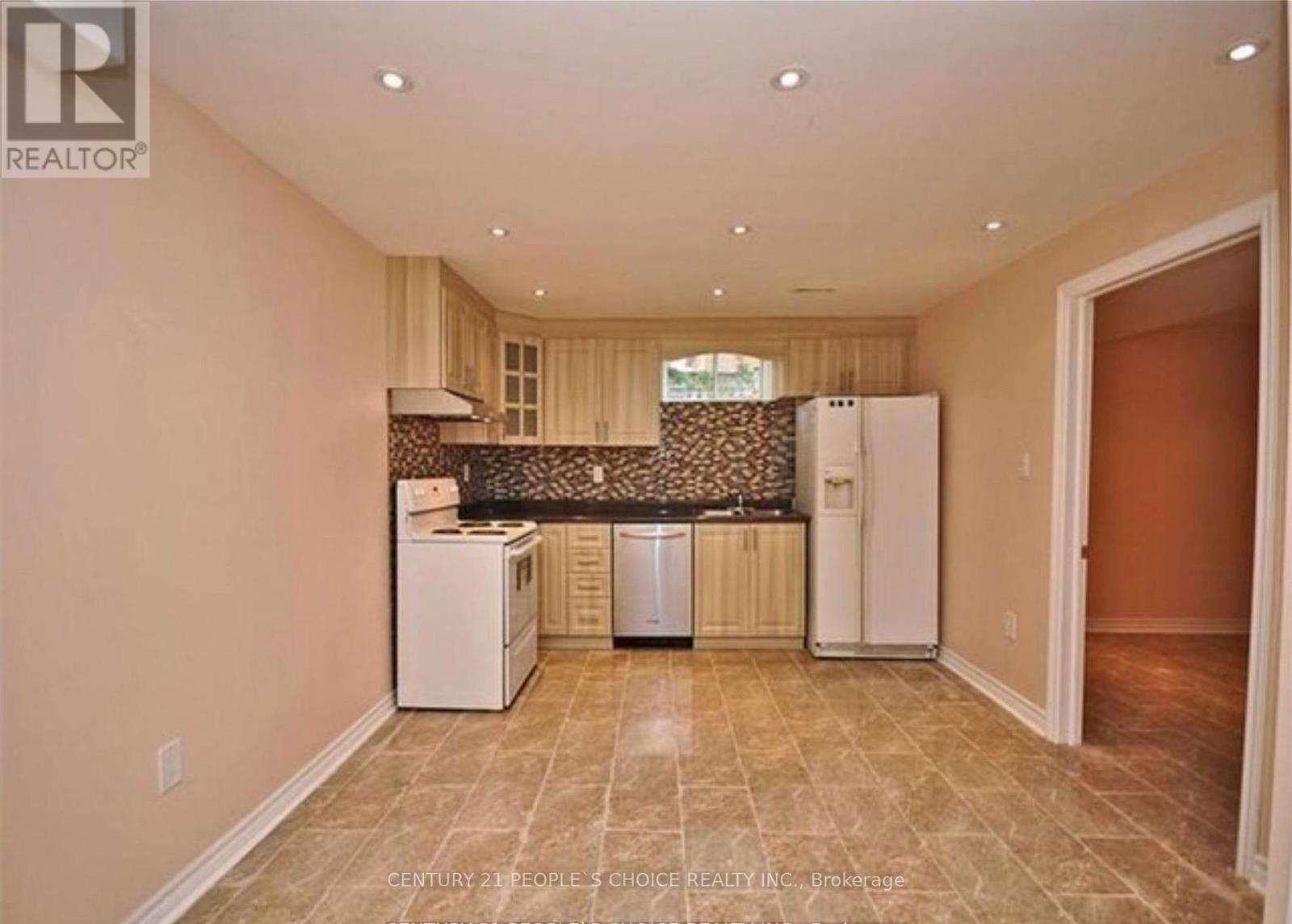 A kitchen area with a dishwasher, a refrigerator, and a washing machine.
