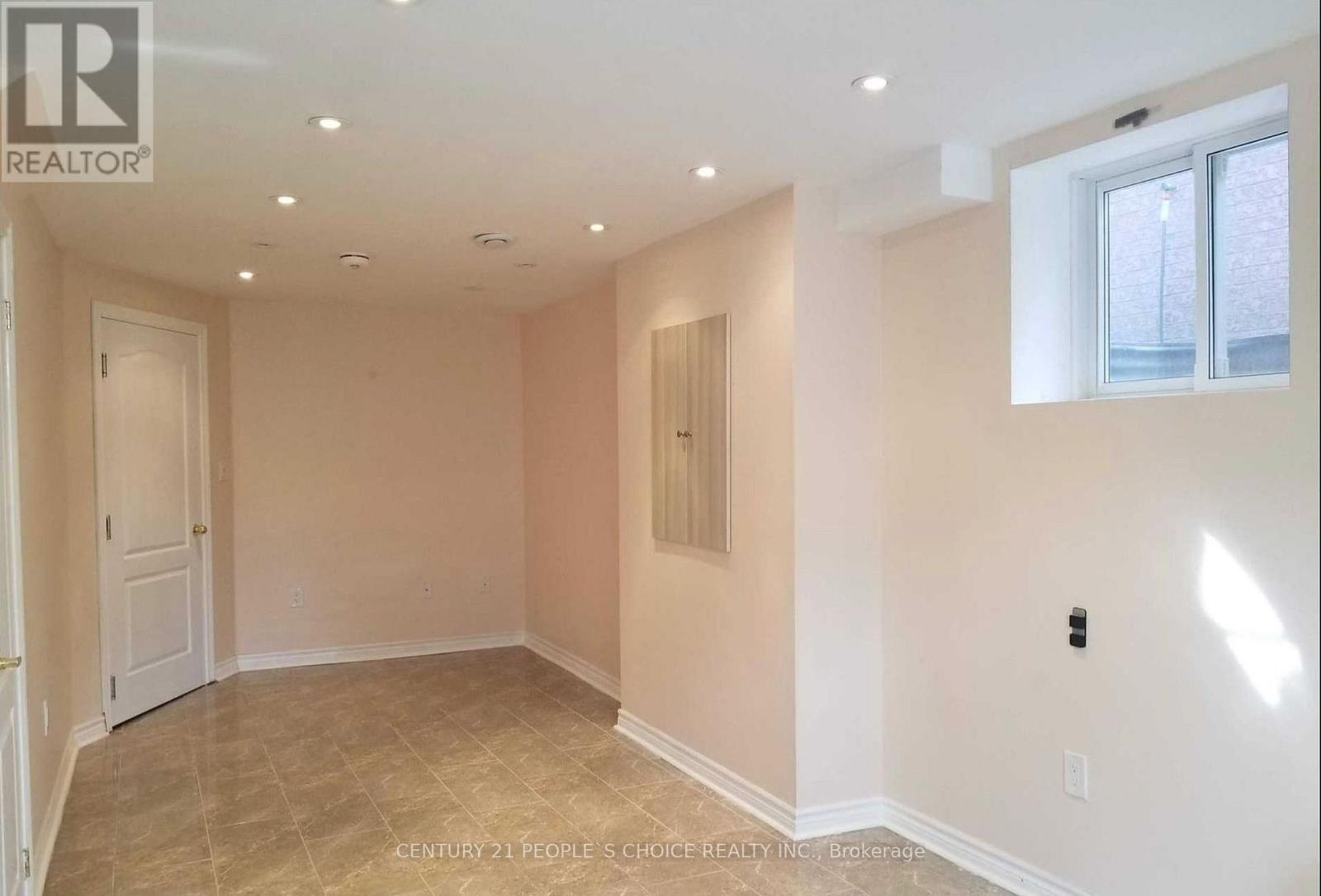 A spacious room with beige walls and a tiled floor.