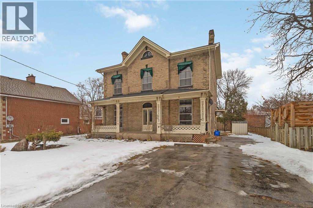 A large, old house with a porch and a snow-covered ground in front.