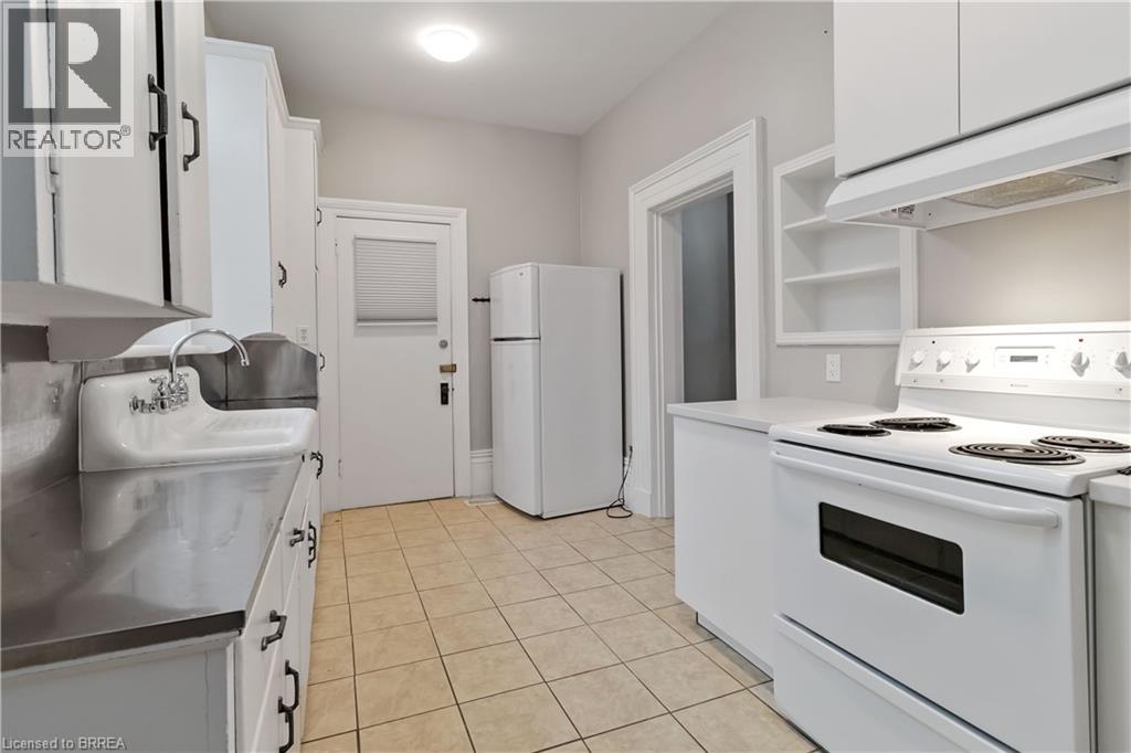 A white kitchen with a stove top oven and a refrigerator.