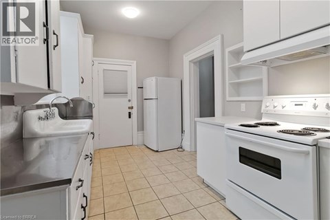 A white kitchen with a stove top oven and a refrigerator.